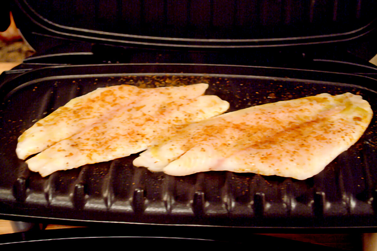 Cooking seasoned fish Ffllets on an electric indoor grill.