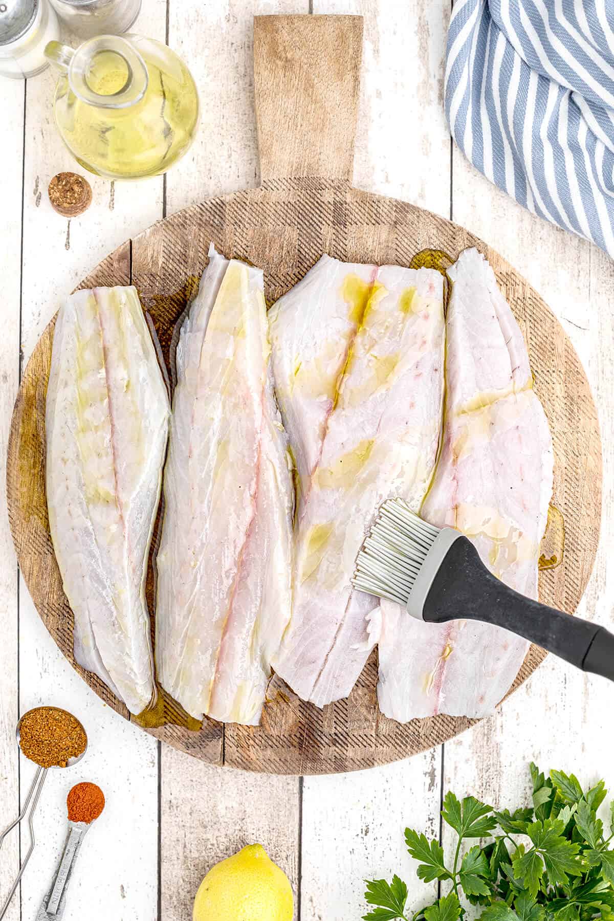 Brushing olive oil on one side of fish fillets.