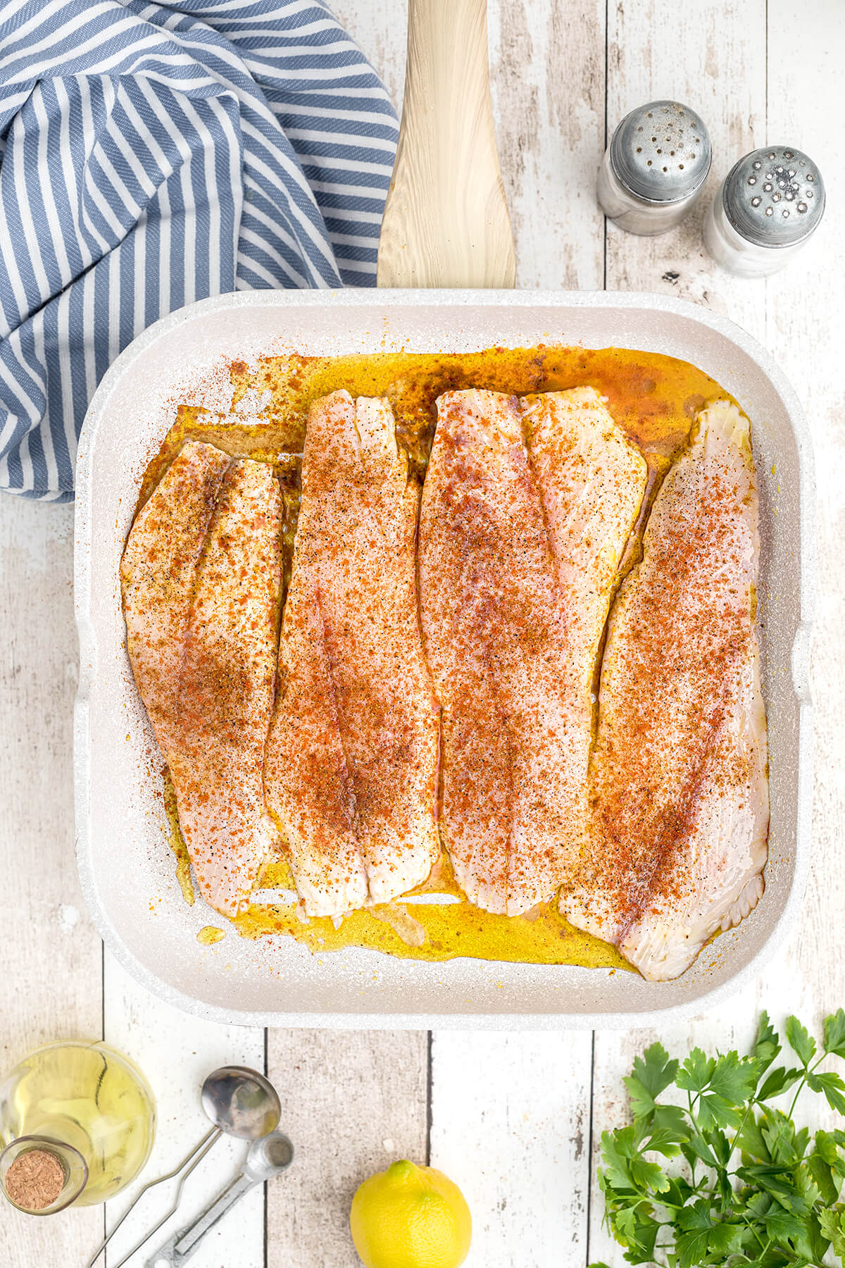 Fish fillets with seasoning applied on a grill pan.