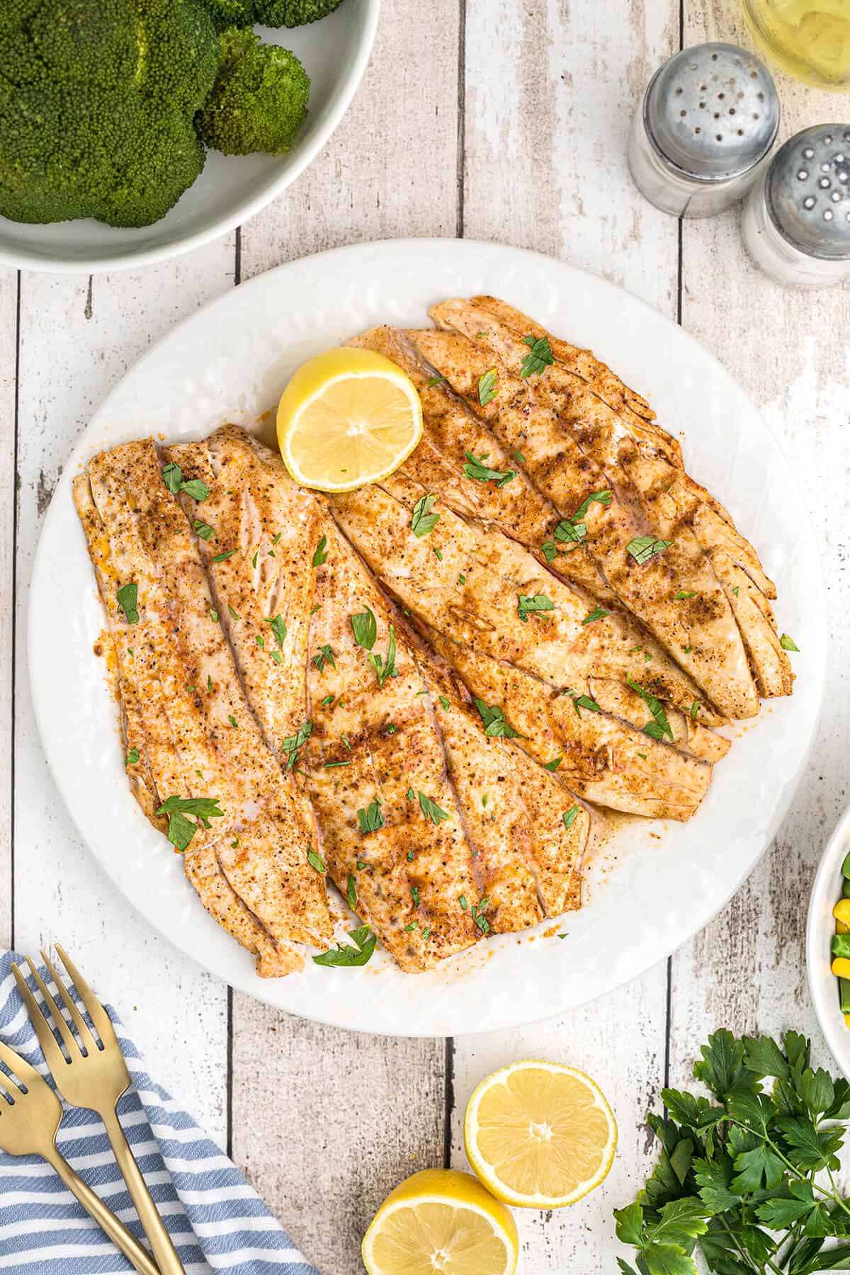 Cooked fish fillets on a plate with a lemon half.