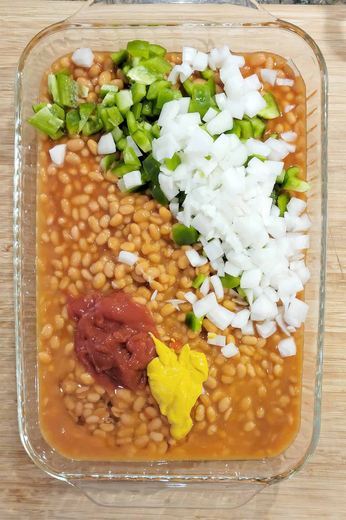 Onions, bell pepper, ketchup, mustard, and syrup added to dish with the beans.