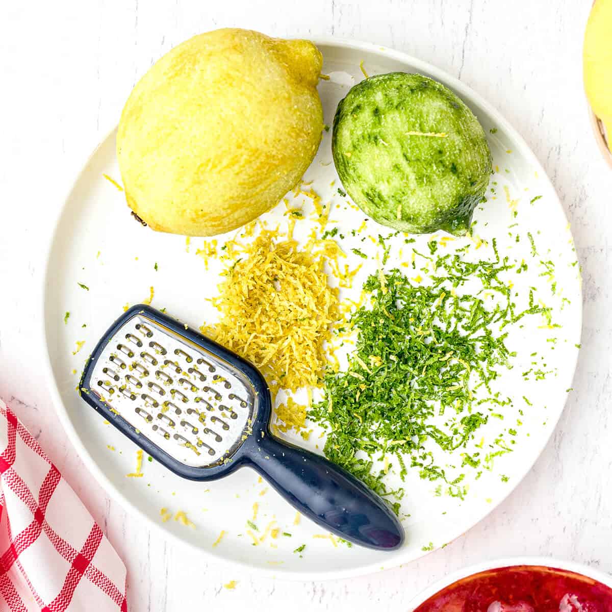 Lemon and lime zest on a plate with a grater.