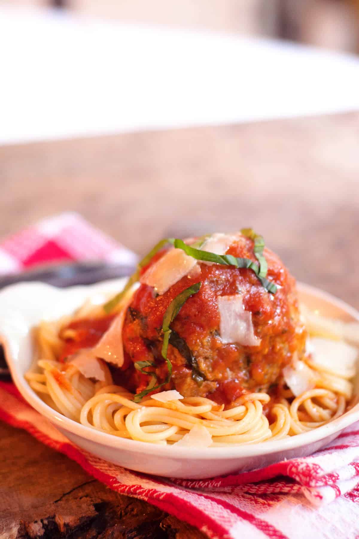 A serving of jumbo meatballs and spaghetti in a white bowl.