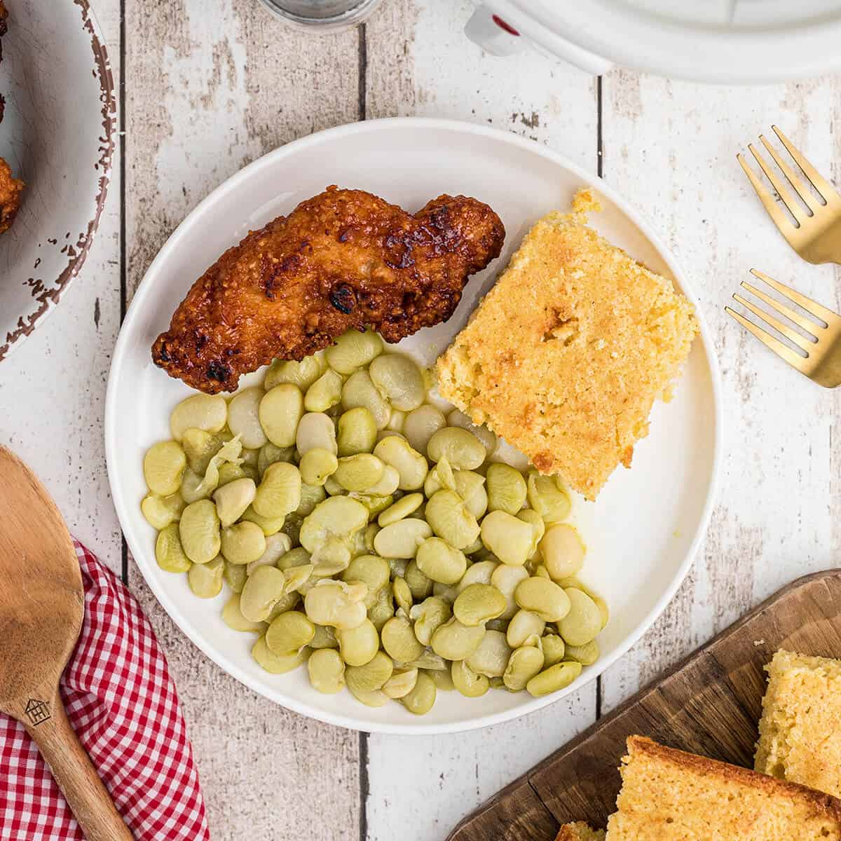 Butter beans on a plate with fried chicken and cornbread.