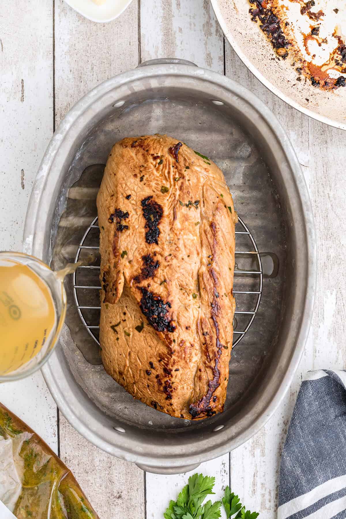 Seared pork loin on a rack in a roasting pan.