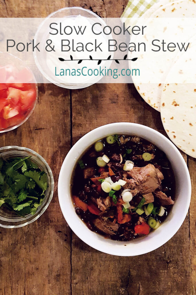 Slow Cooker Pork and Black Bean Stew in a serving bowl with garnishes on the side.
