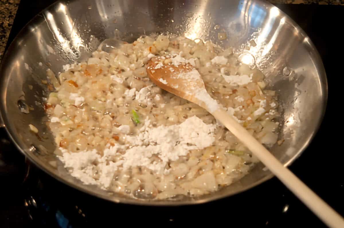 Flour added to onions in a skillet.