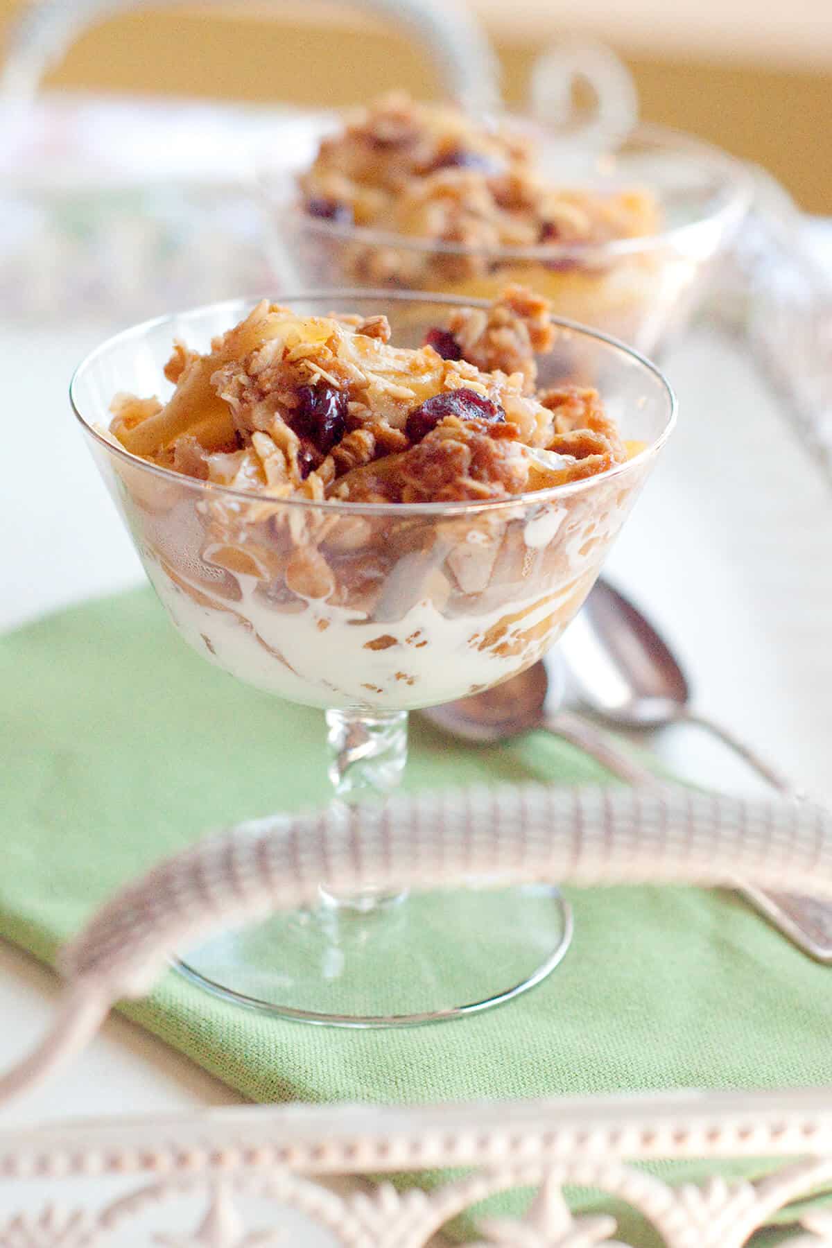 A serving of apple cranberry crisp in a crystal dish.