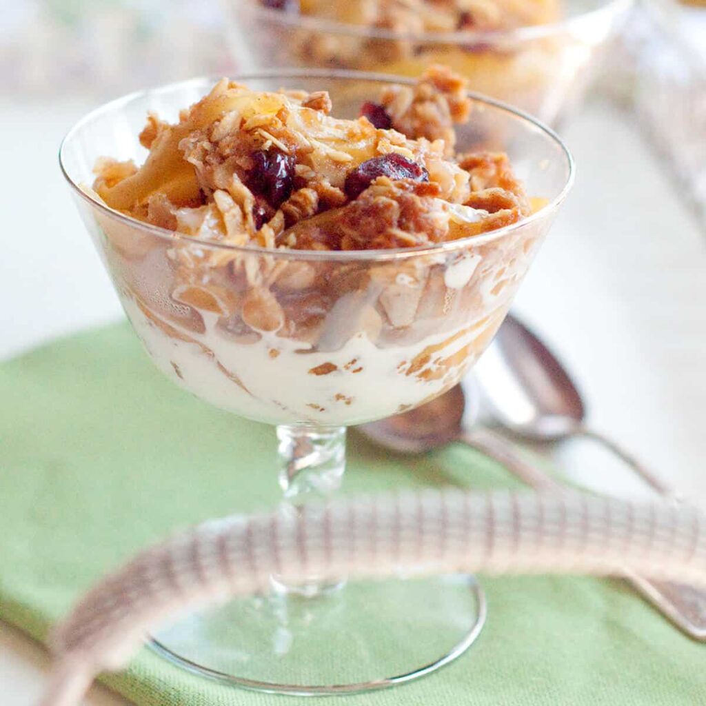 A serving of apple cranberry crisp in a crystal dish.