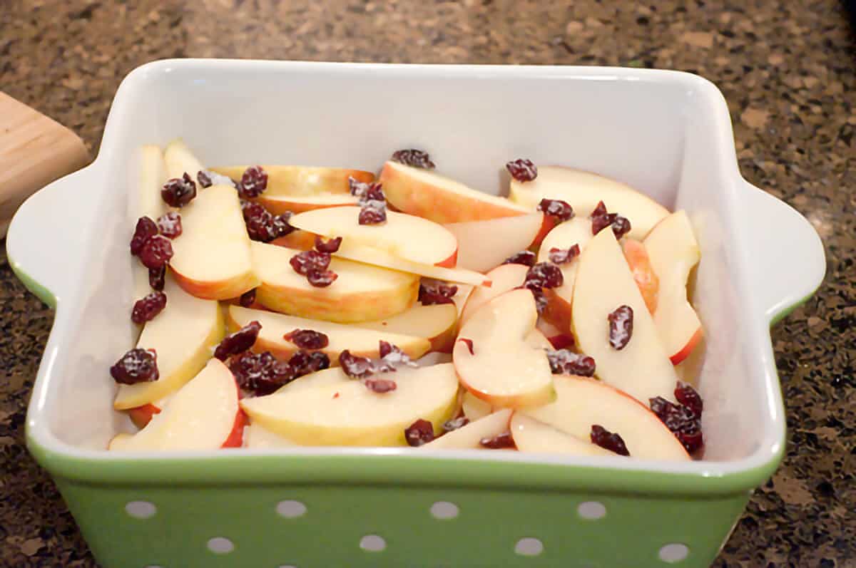 Sliced apples and cranberries in a baking dish.
