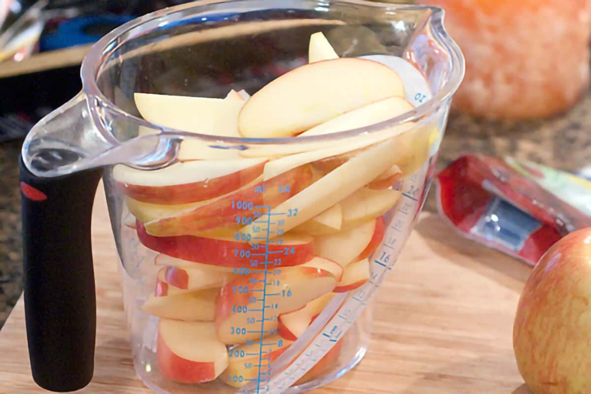 Sliced apples in a measuring cup.