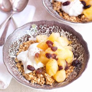 A serving of apple-pear compote with yogurt and granola in a decorative bowl.