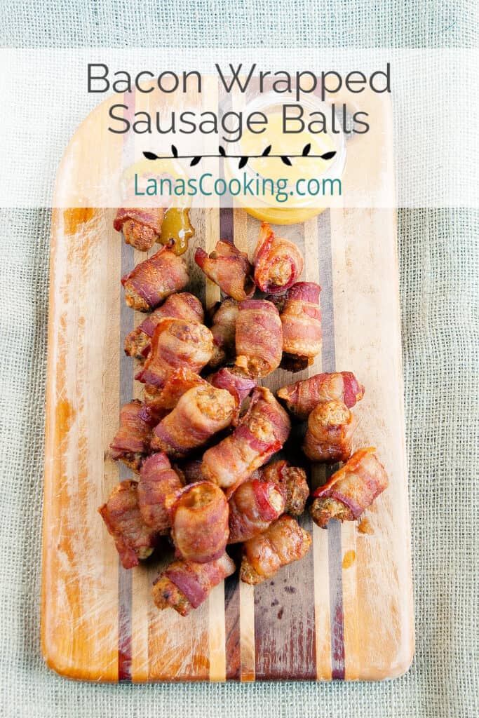 Bacon wrapped sausage balls and dipping sauce on a wooden board.