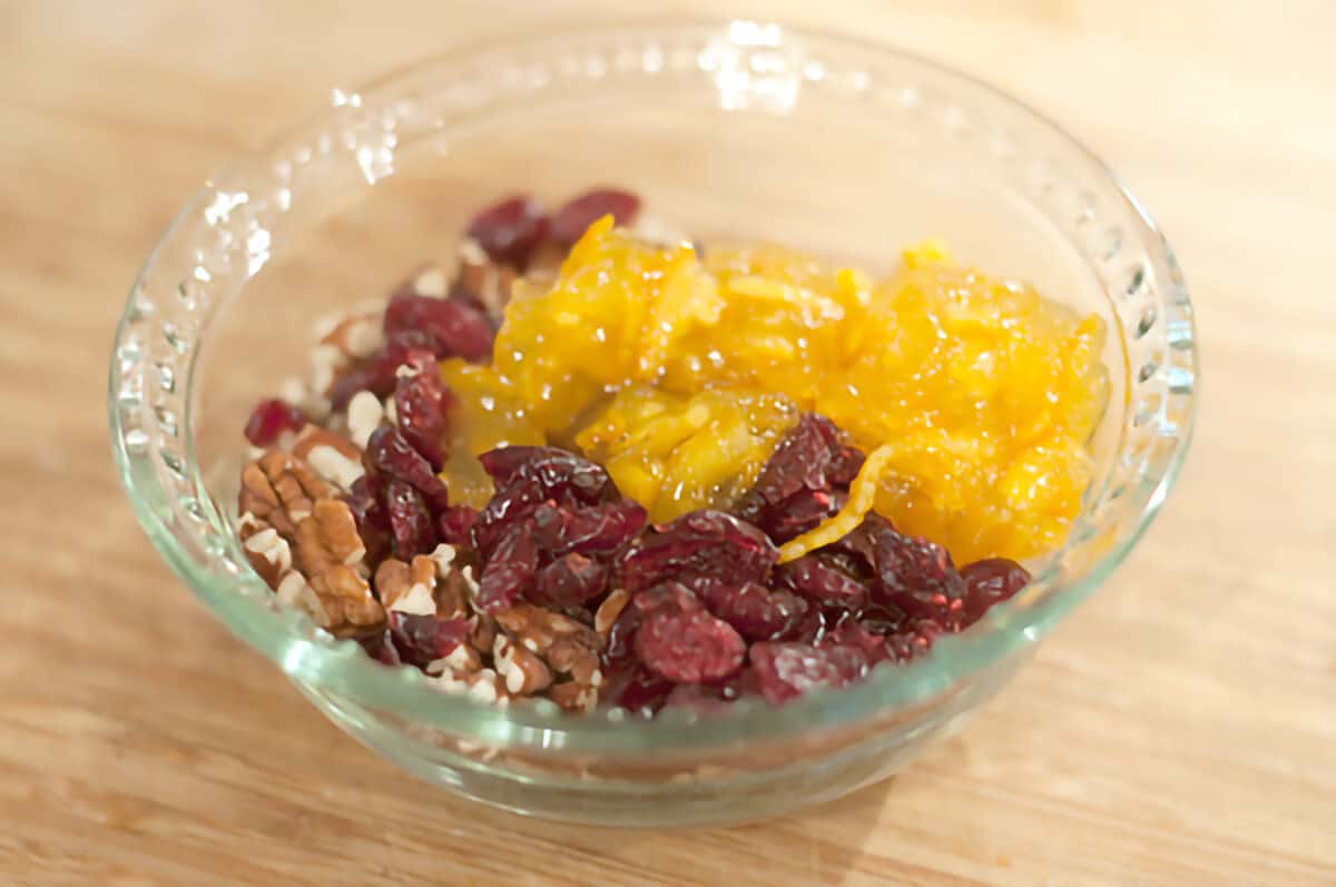 Small glass bowl with cranberries, pecans, and orange marmalade.