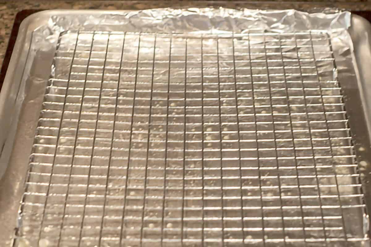 A cooling rack inside a baking sheet lined with foil.