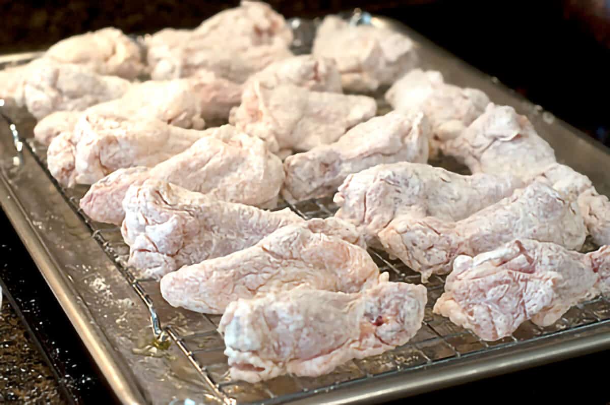 Coated wings on the rack inside the baking sheet.