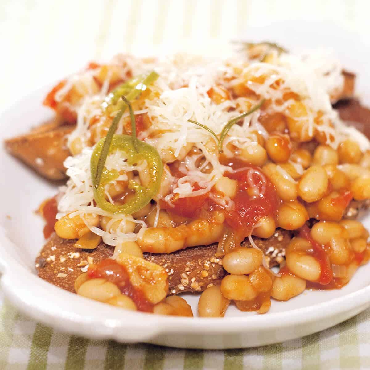 A serving of beans on toast on a white plate.