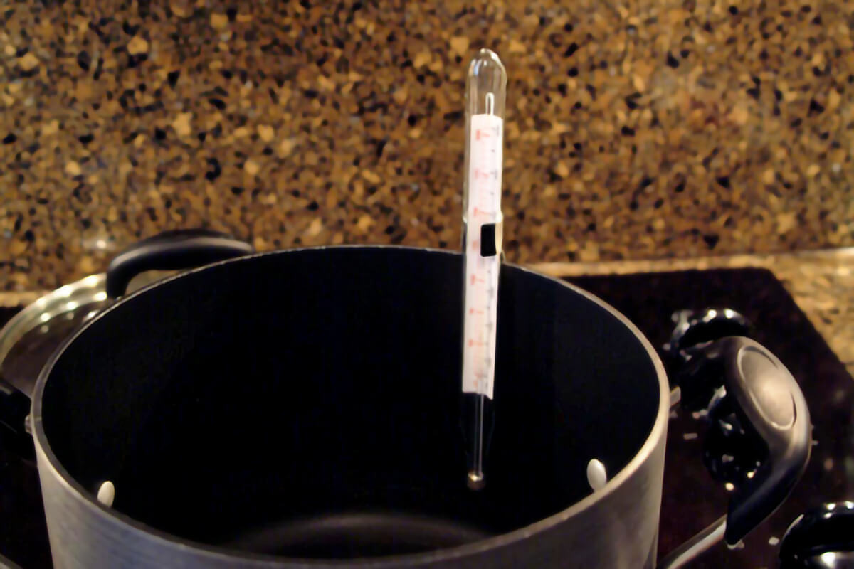 Candy thermometer attached to a saucepan.