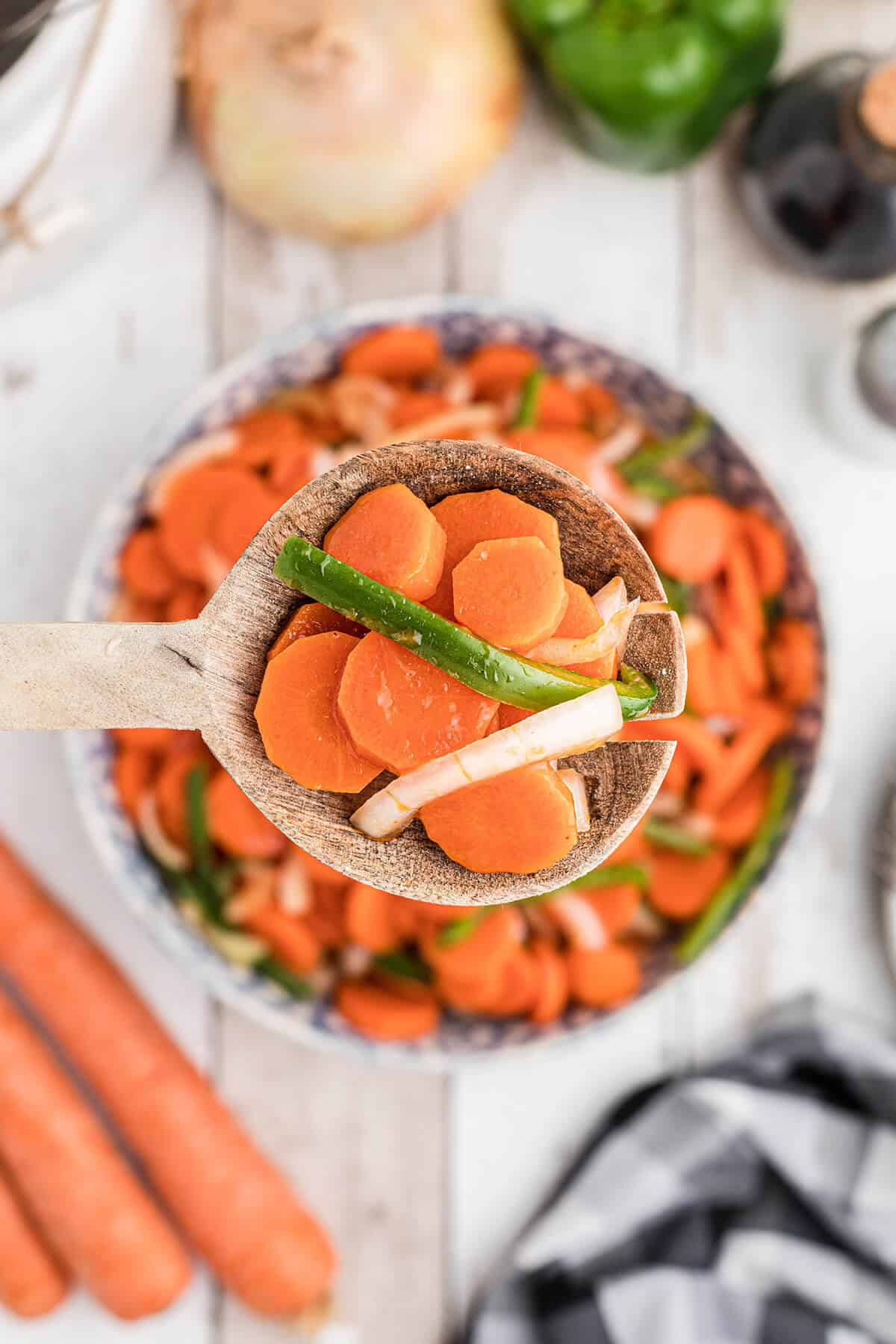 Wooden spoon holding a bite of marinated carrot salad.