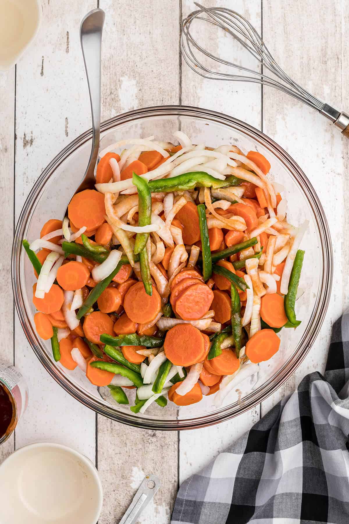 Veggies added to the marinade in a mixing bowl.