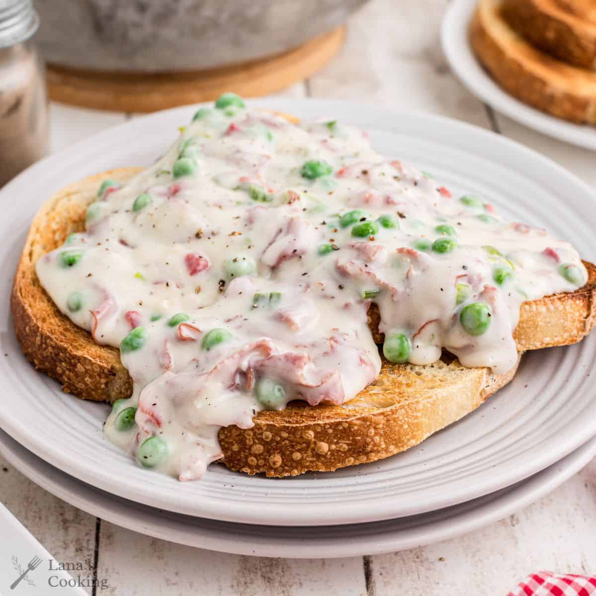 Creamed chipped beef, also known as SOS, on toast sitting on a white plate.