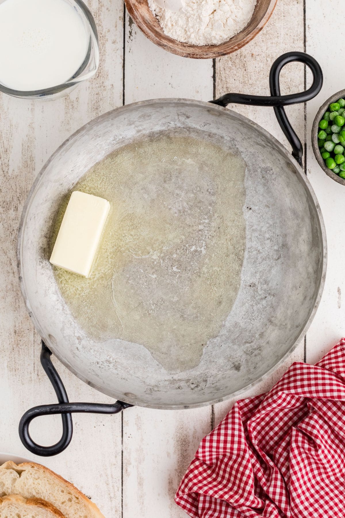 Butter melting in a large skillet on a wooden background.