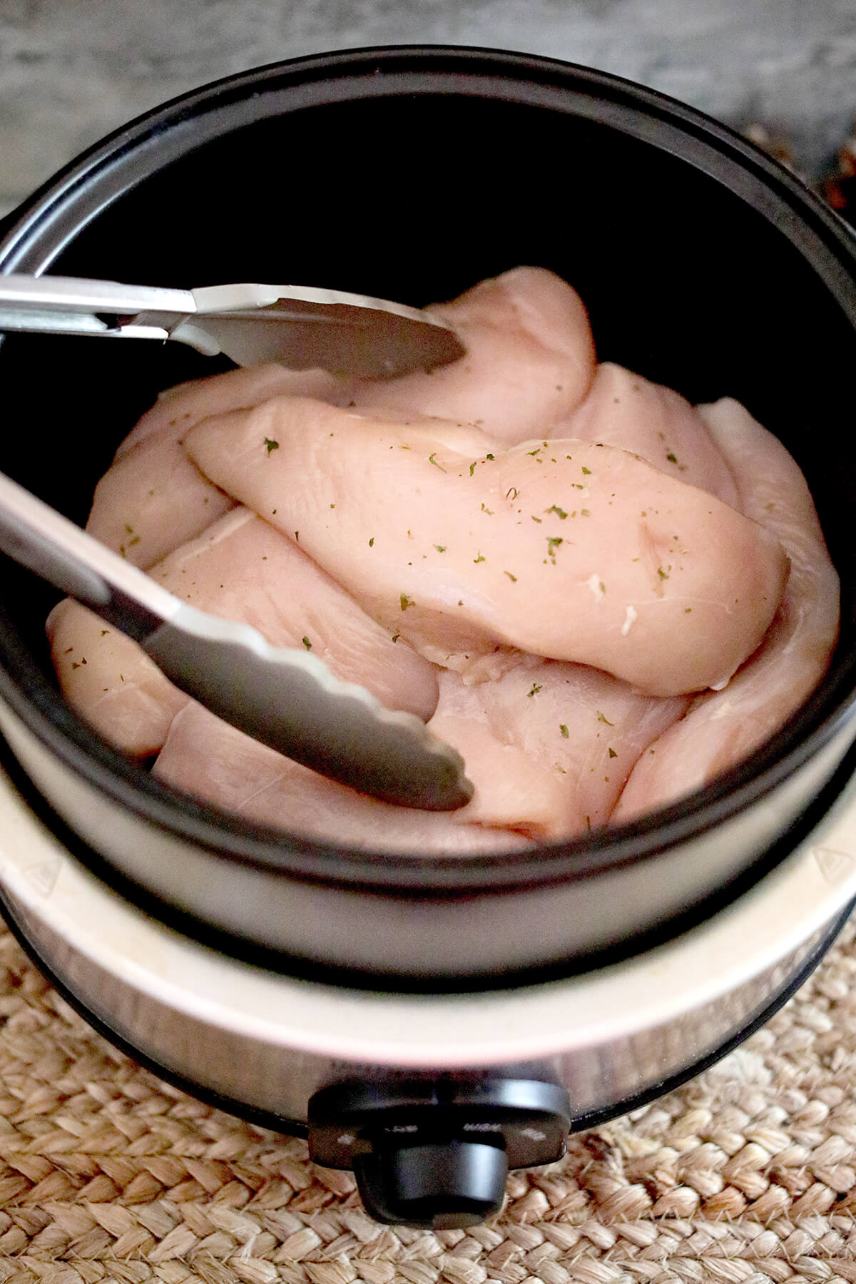 Chicken breasts added to a slow cooker.