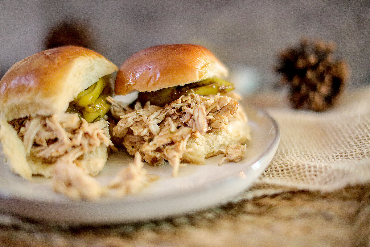 Two chicken sliders with pepperoncini on a serving plate.