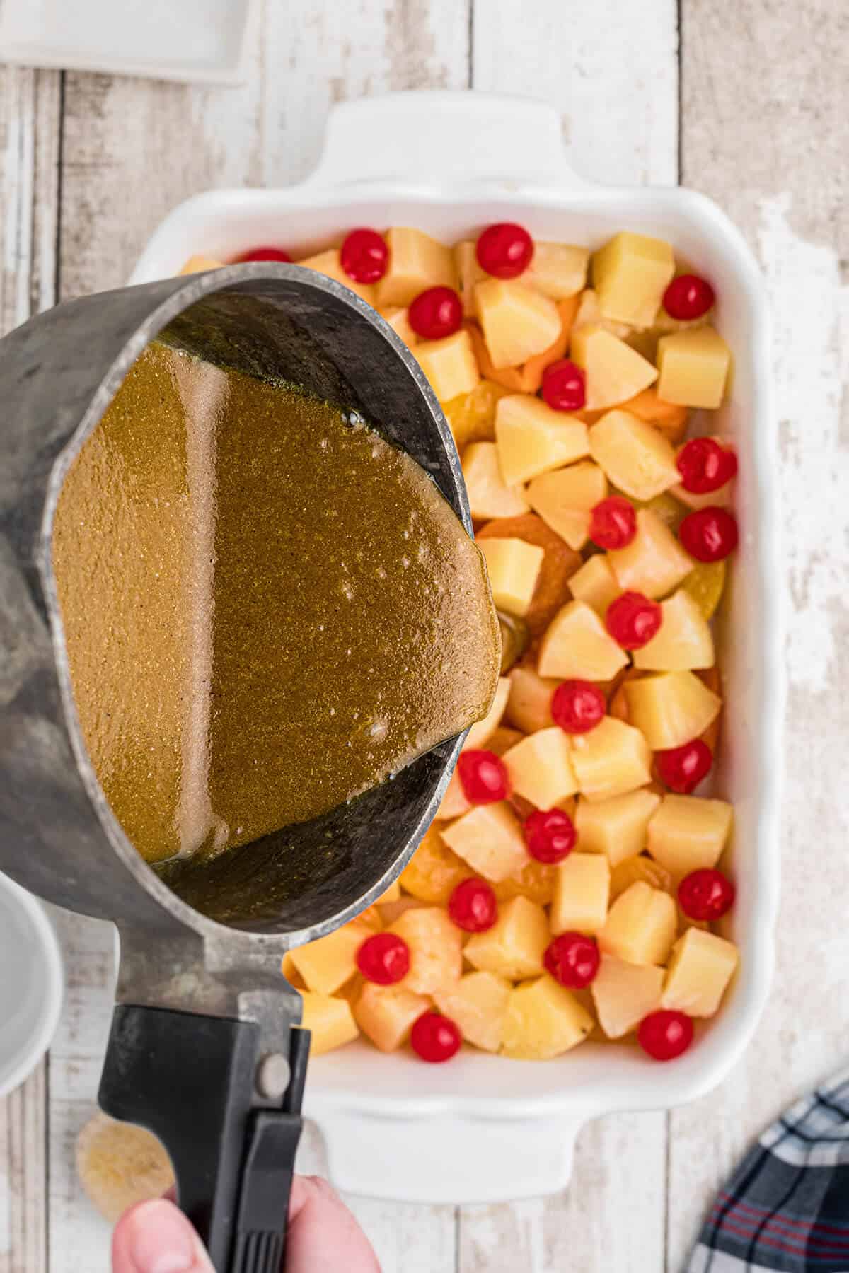 Pouring curry mixture over fruit.