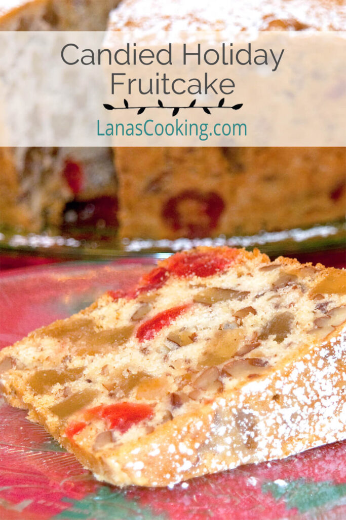 A slice of candied holiday fruitcake on a plate with remaining cake in background. Text overlay for pinning.