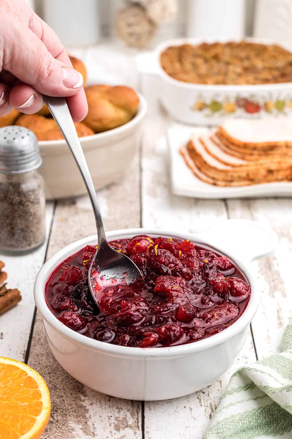 Cranberry orange sauce in a white serving dish with a spoon.