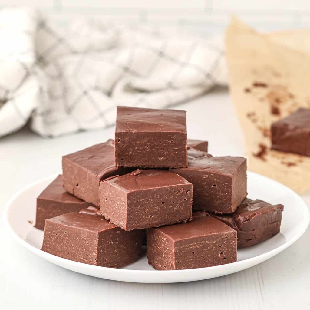 Squares of chocolate fudge on a white serving plate.