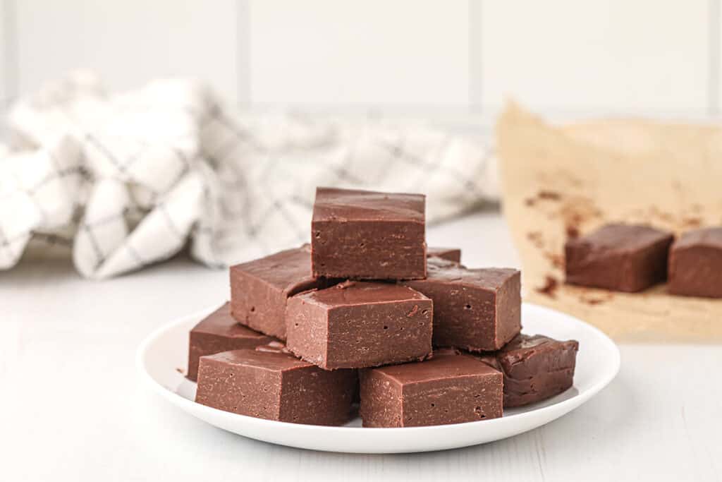 Squares of chocolate fudge on a white serving plate.