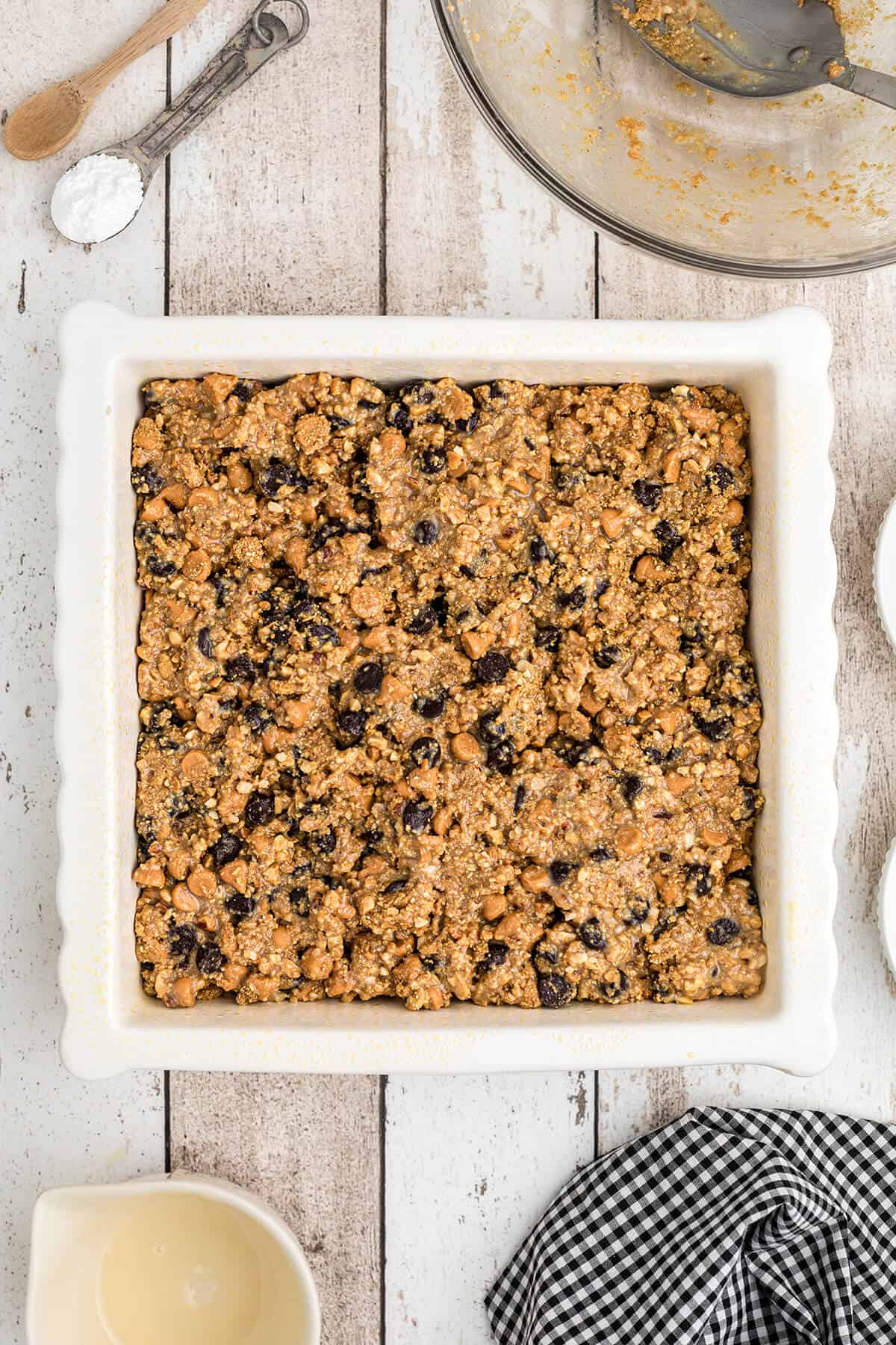 Pressing cookie mixture into a prepared baking dish.