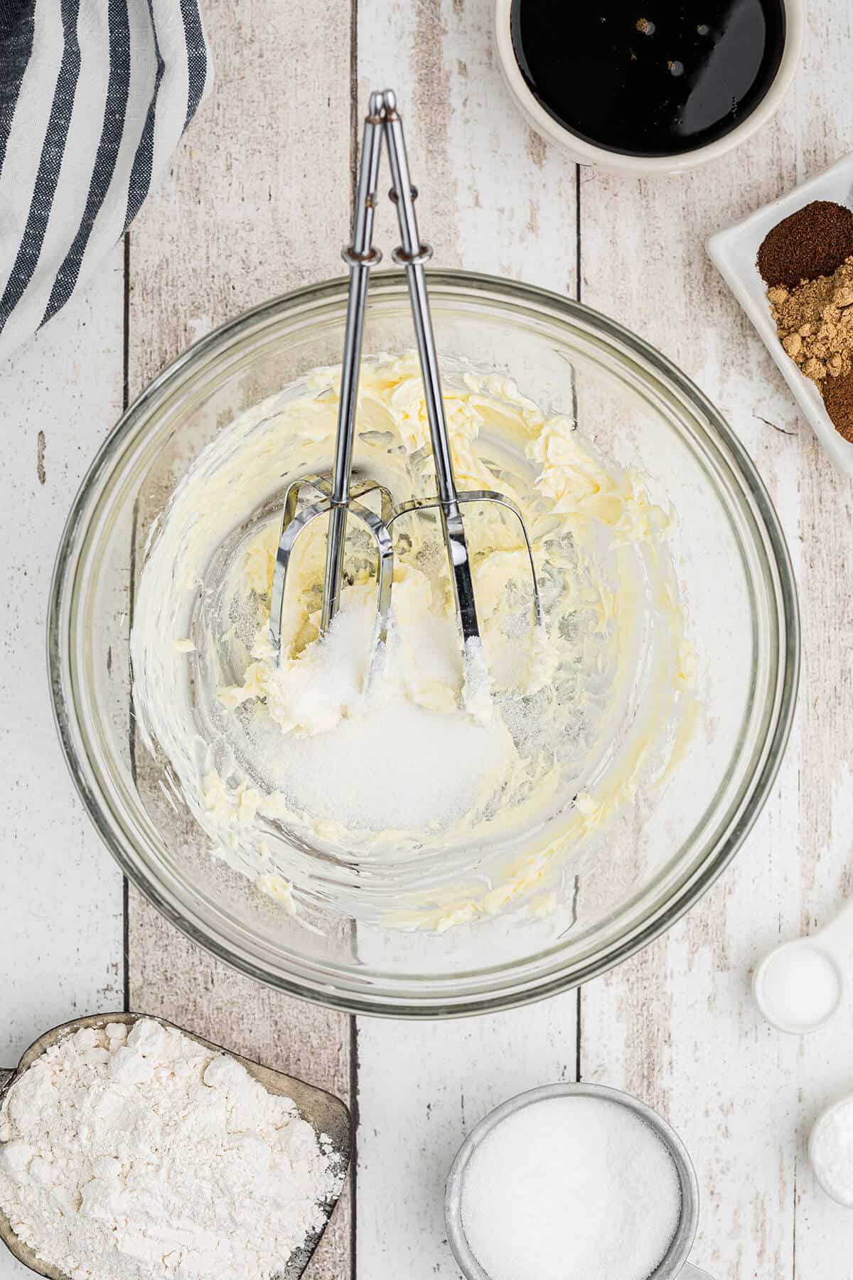Sugar added to butter in a mixing bowl.