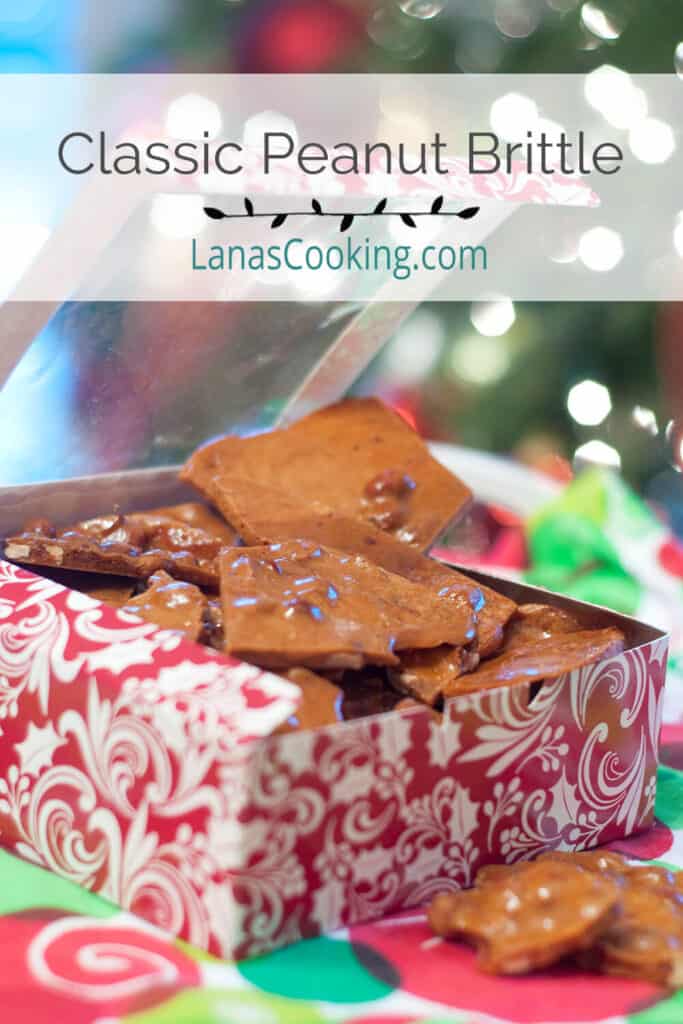 Peanut brittle in a candy gift box with Christmas tree lights in the background.