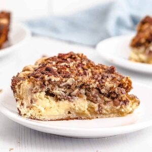 A slice of pecan cheesecake pie on a white serving plate.