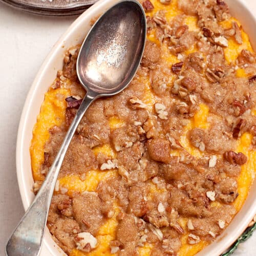 Sweet potato casserole in a baking dish with a vintage serving spoon.