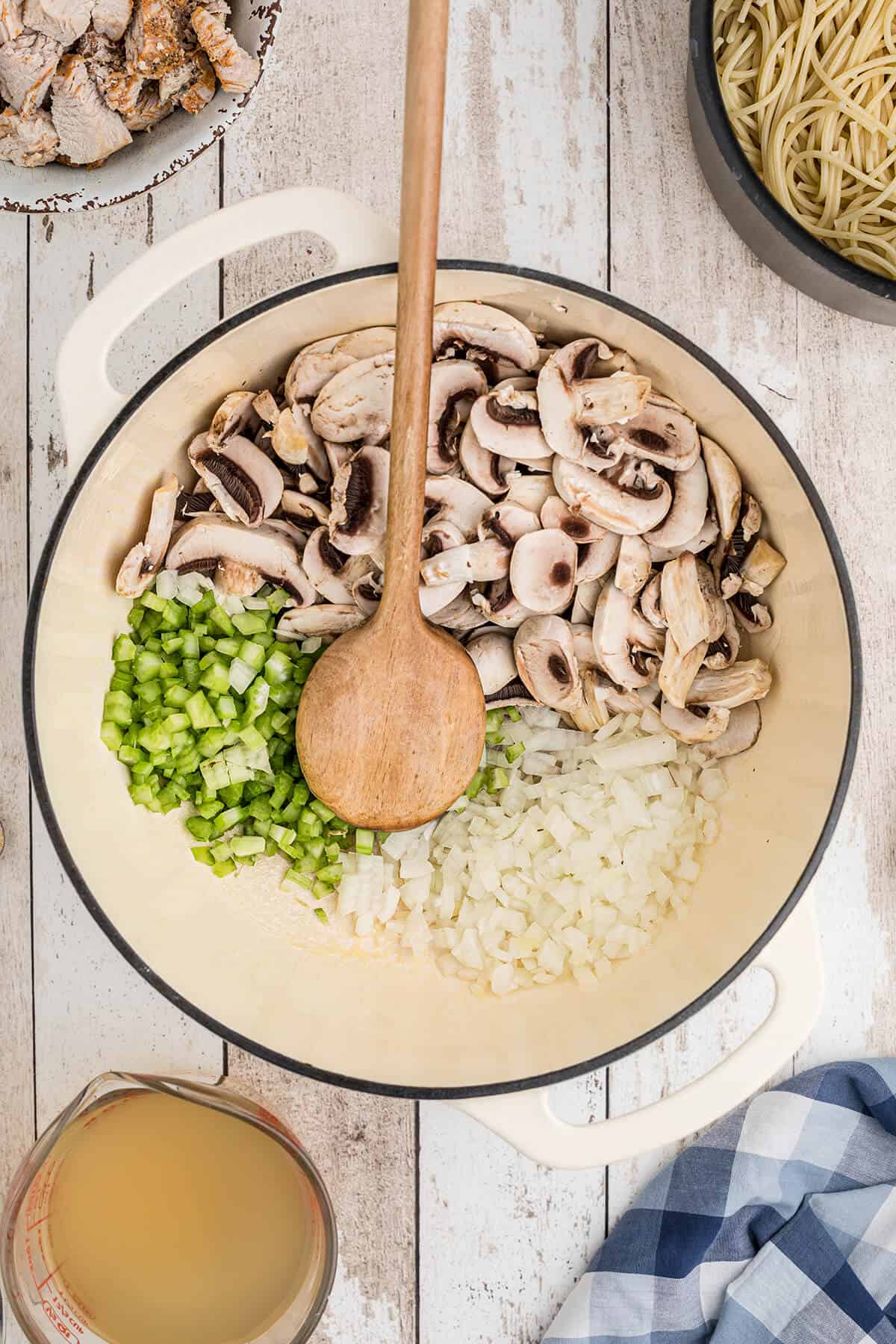 Onions, celery, and mushrooms cooking in a large saucepan.