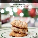 Three almond joy cookies stacked on a plate with a festive, blurred holiday background.
