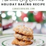 Three almond joy cookies stacked on a holiday plate with festive lights in the background.