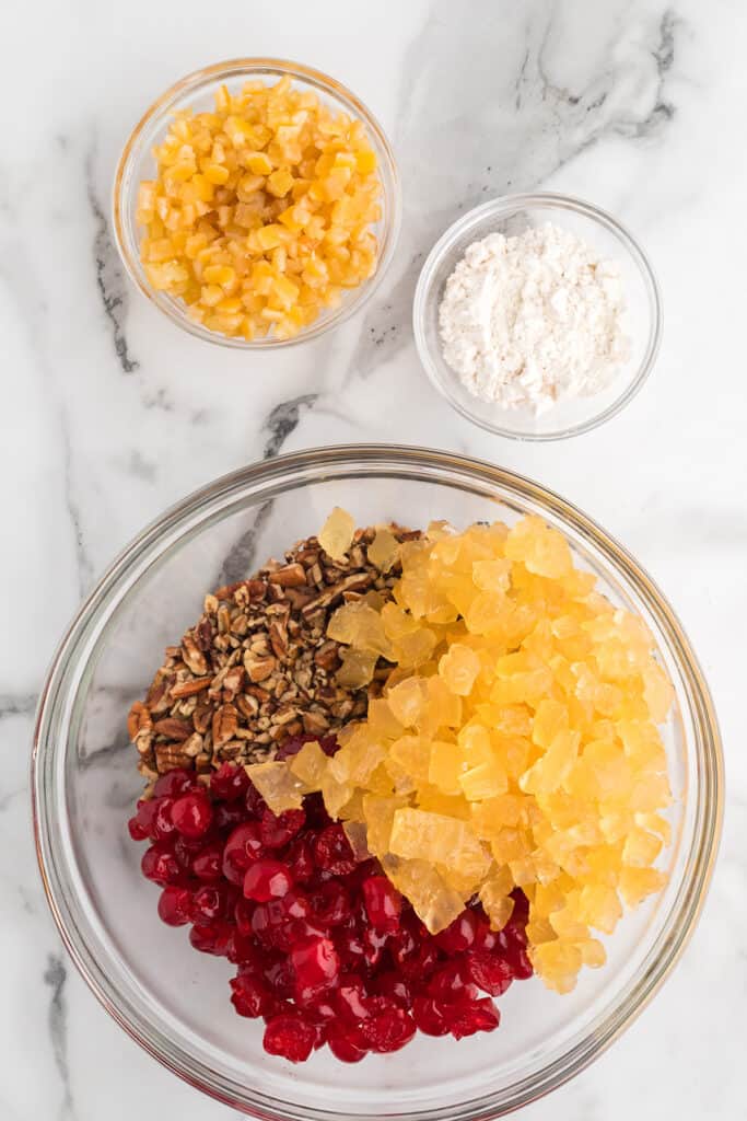Chopped pineapple and cherries in a mixing bowl.
