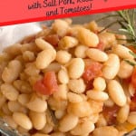 A serving of beans and tomatoes in a clear glass bowl.