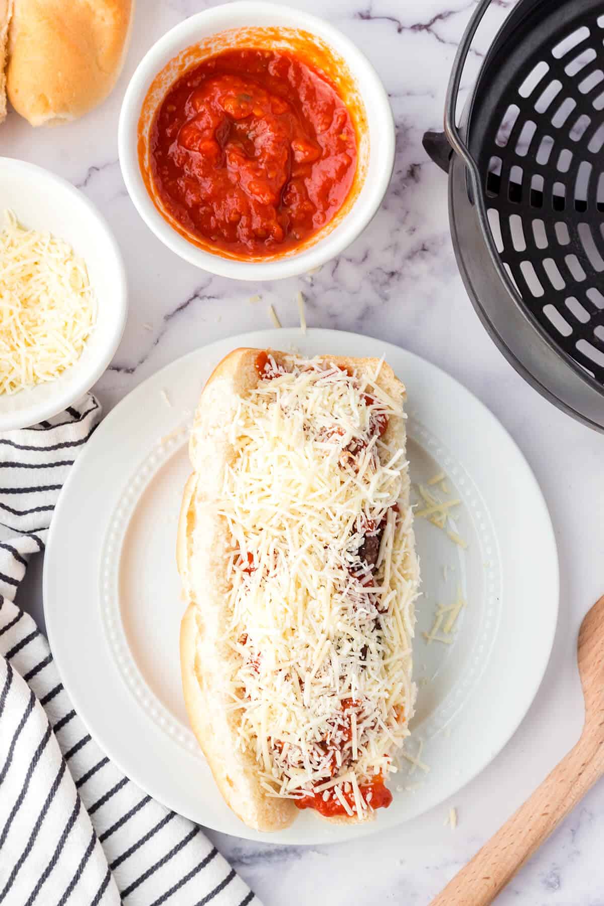 Hoagie roll and meatballs covered with marinara and cheese.