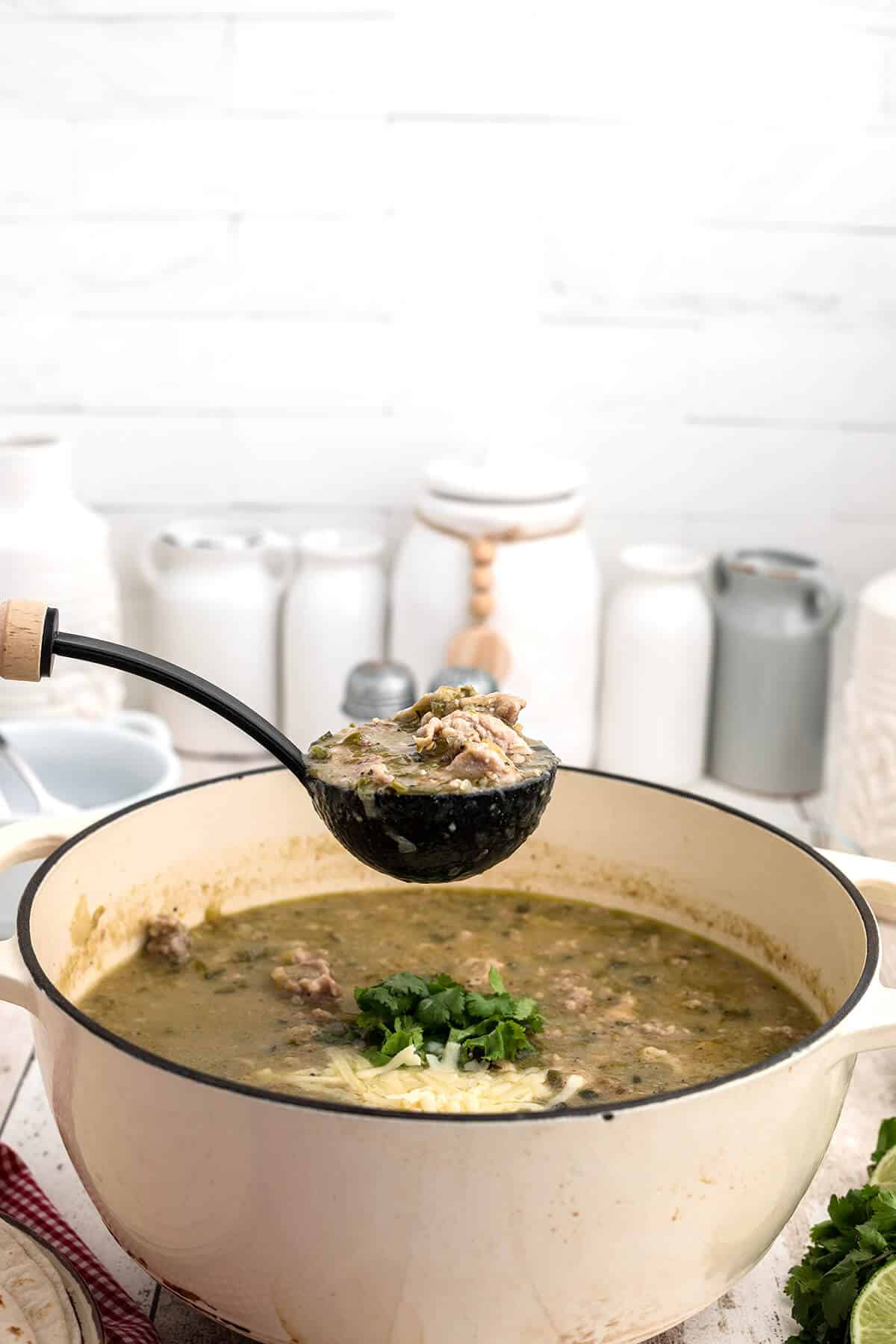 A ladle of chili over a pot of finished chili verde.