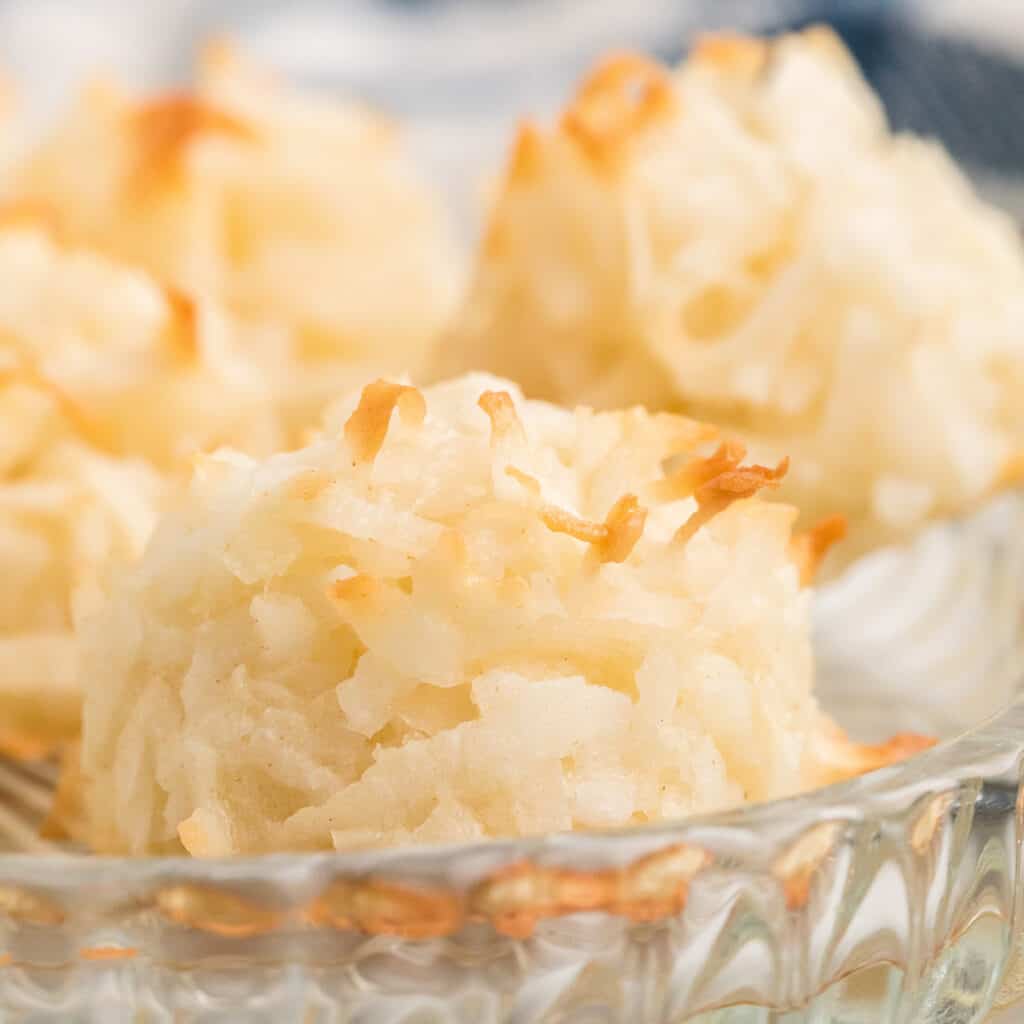 Close-up of coconut macaroons on a glass plate, showing their golden, toasted edges.
