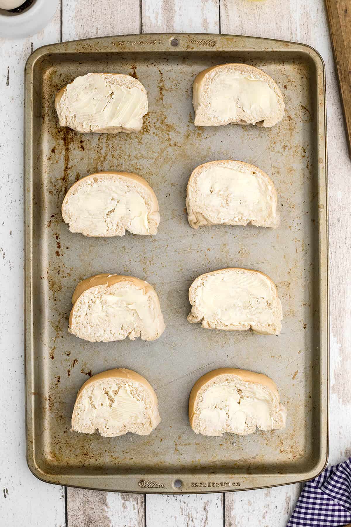 A baking sheet with slices of buttered bread.