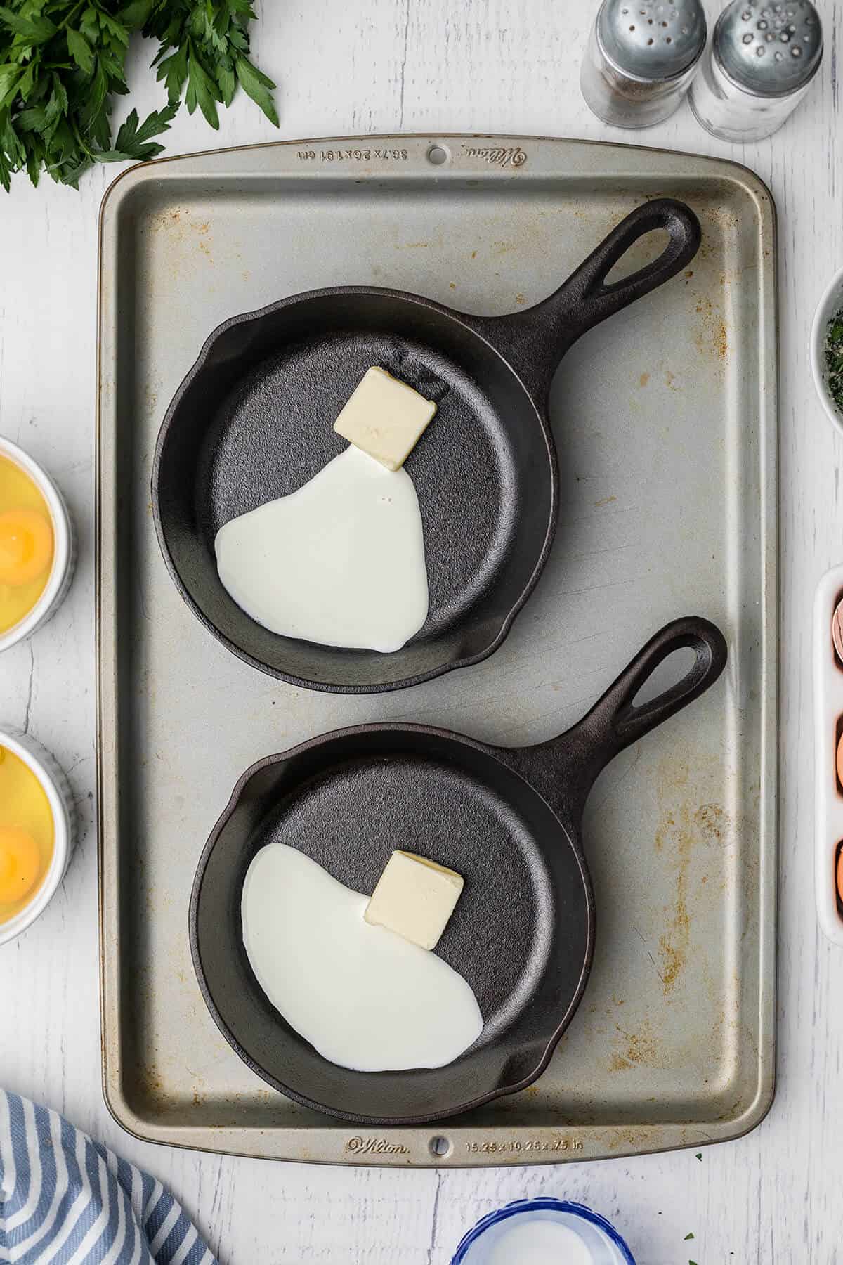 Butter and cream in two mini skillets on a baking pan.