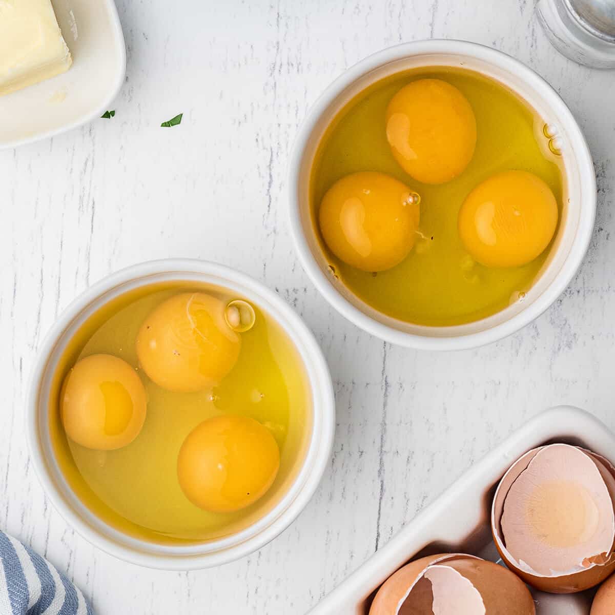 Six eggs cracked into two small bowls.