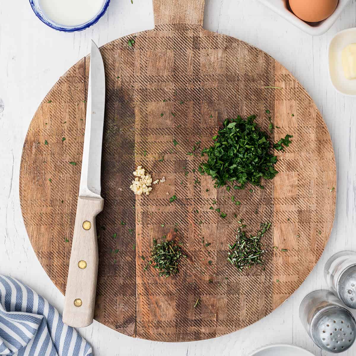 Minced garlic and herbs on a wooden board.